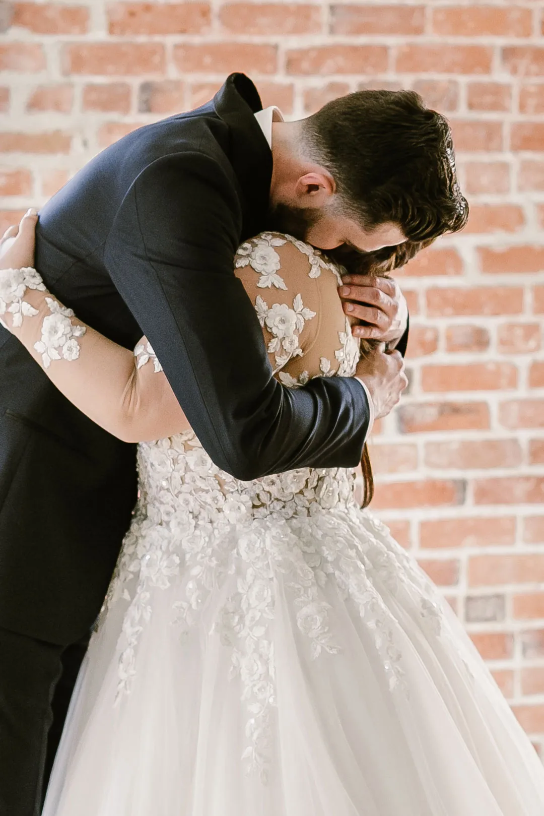 Newlyweds embracing in a brick-walled room