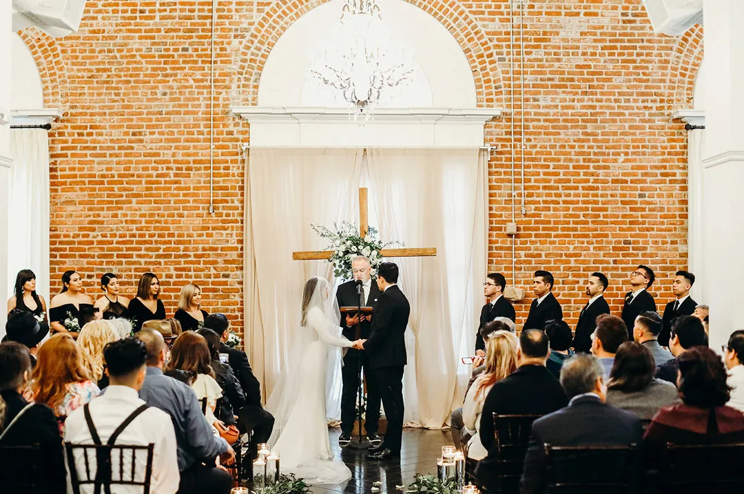 Guests seated for a wedding ceremony beneath an arched window