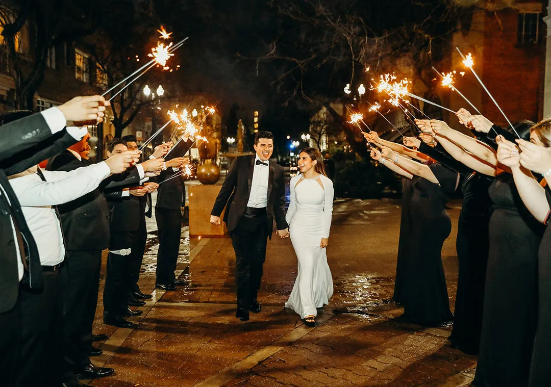 Couple walking through a tunnel of raised sparklers at night