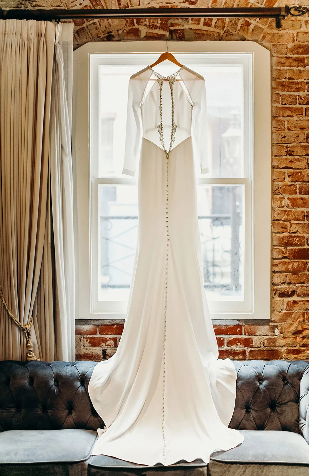 Wedding dress hanging in front of a tall window