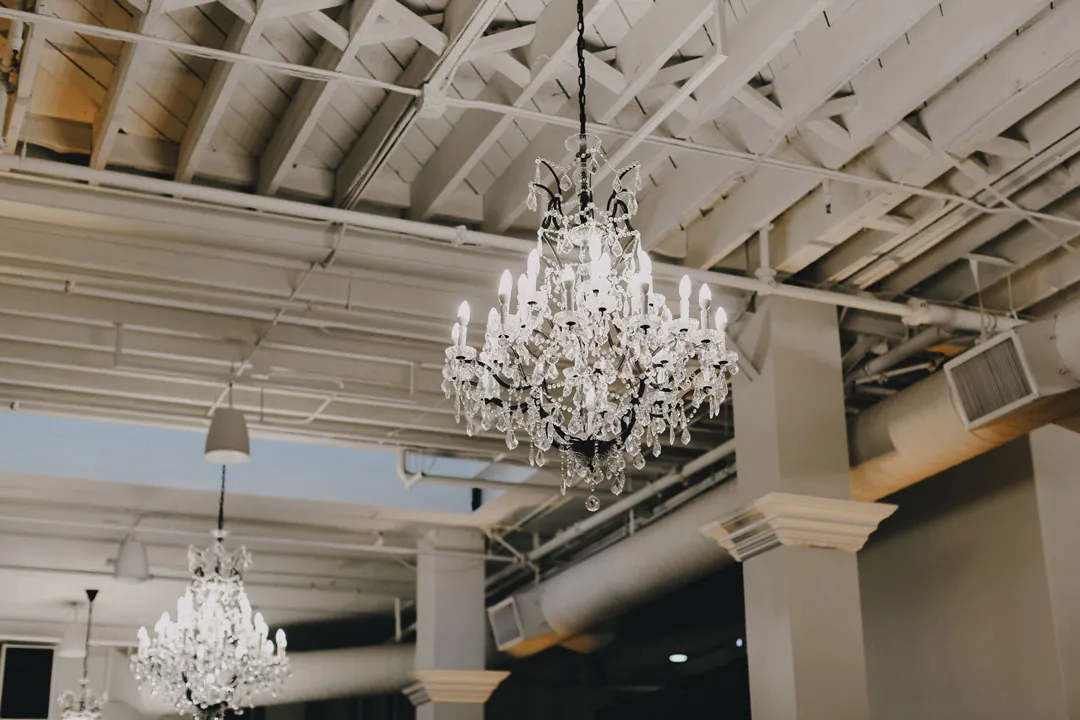 Crystal chandelier beneath exposed white ceiling beams