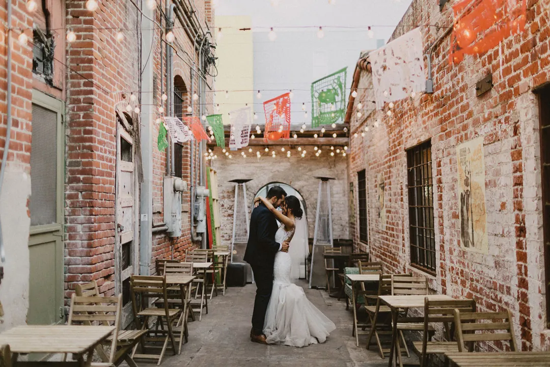 Bride and groom kissing in a brick-lined courtyard