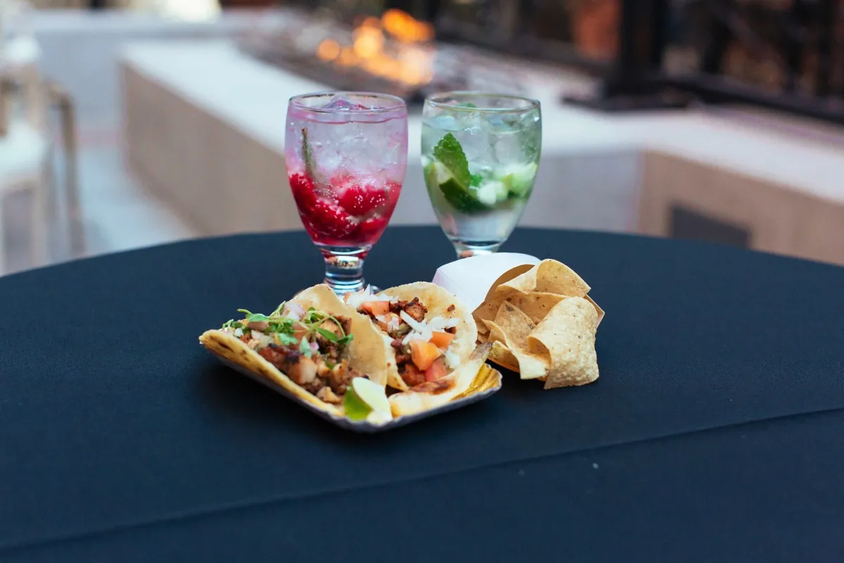 Small plates of food beside red and green drinks