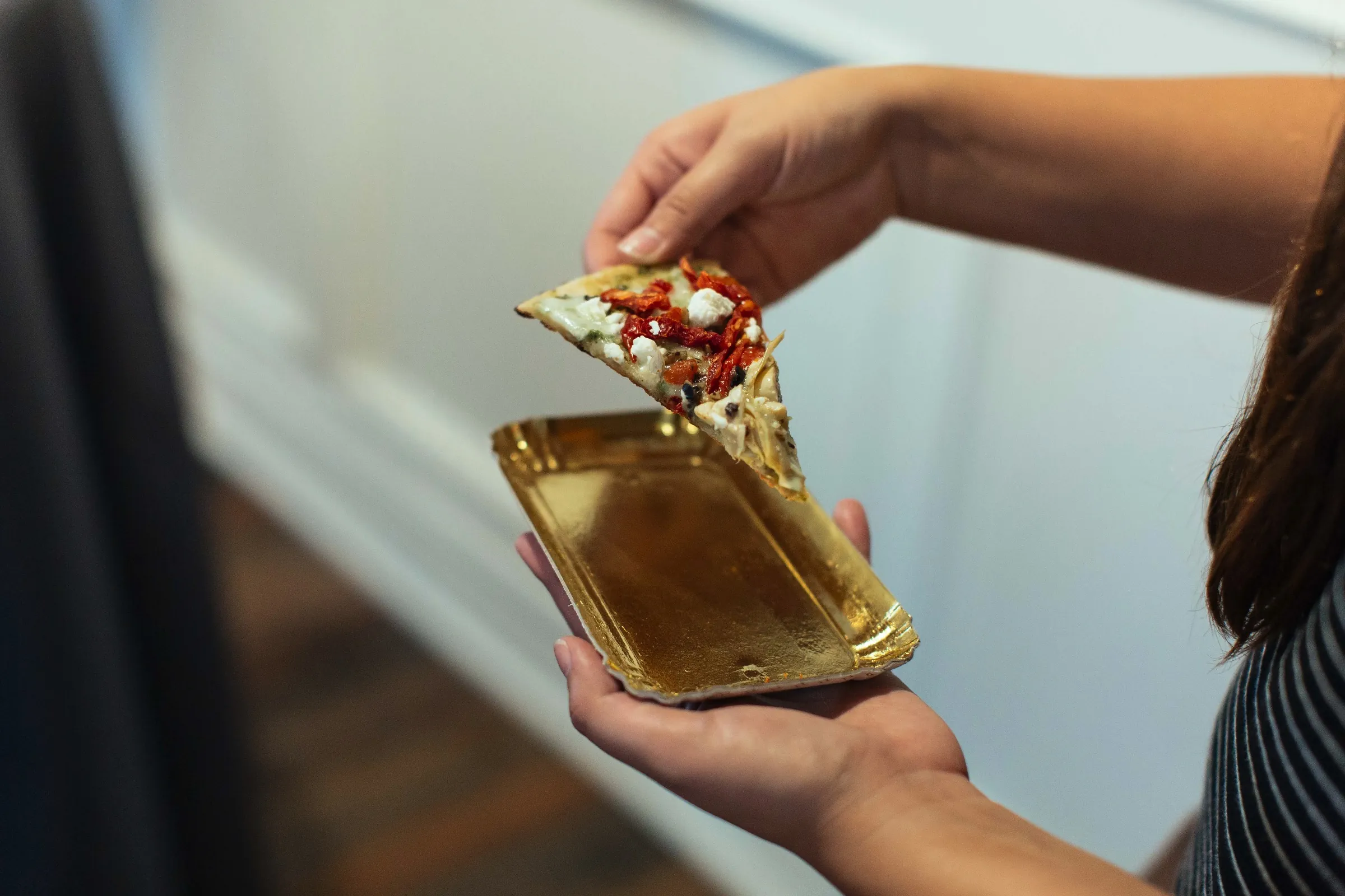 Guest lifting a small savory dish from a gold plate