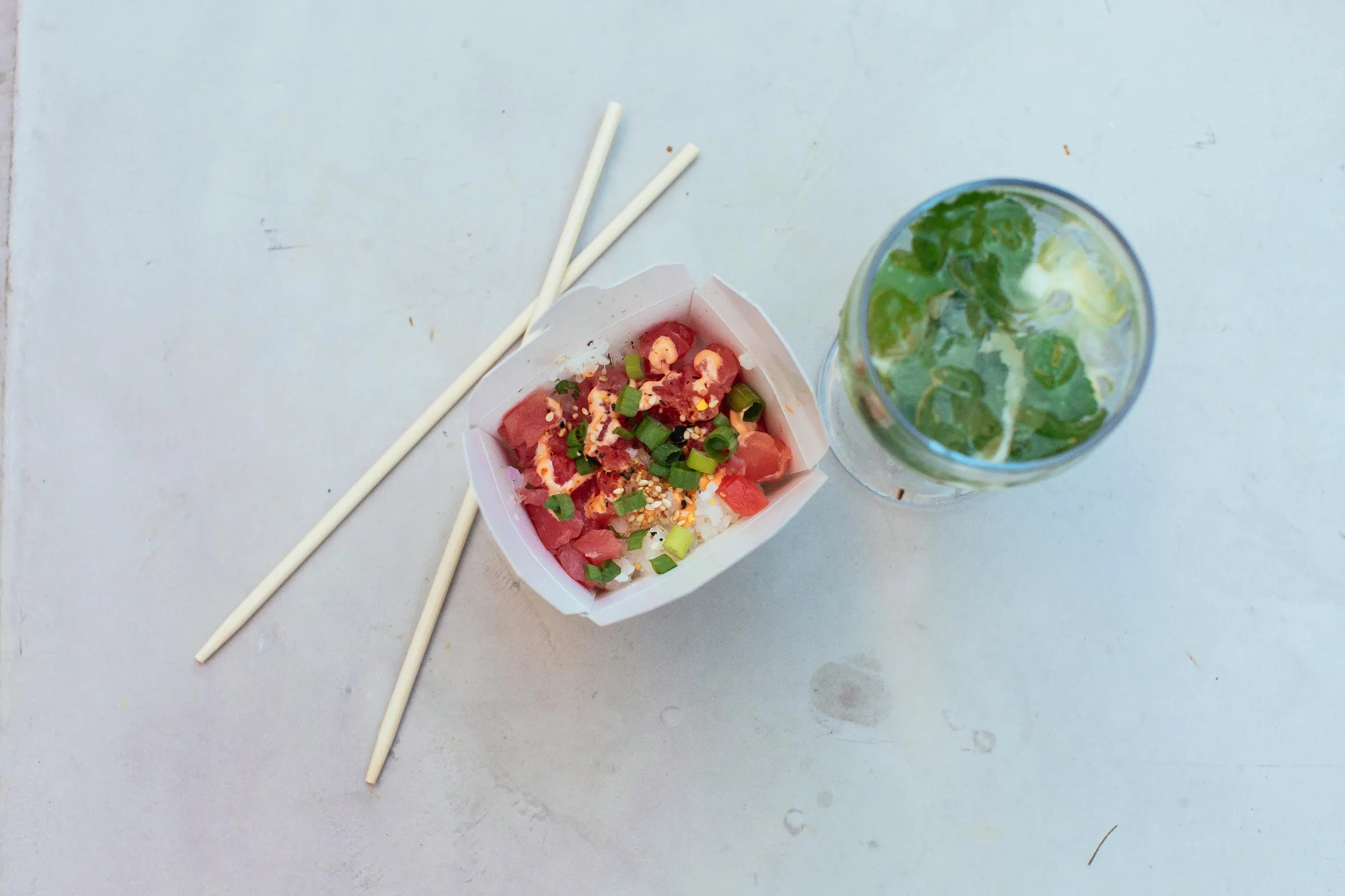 Small savory dish and chopsticks beside a green drink