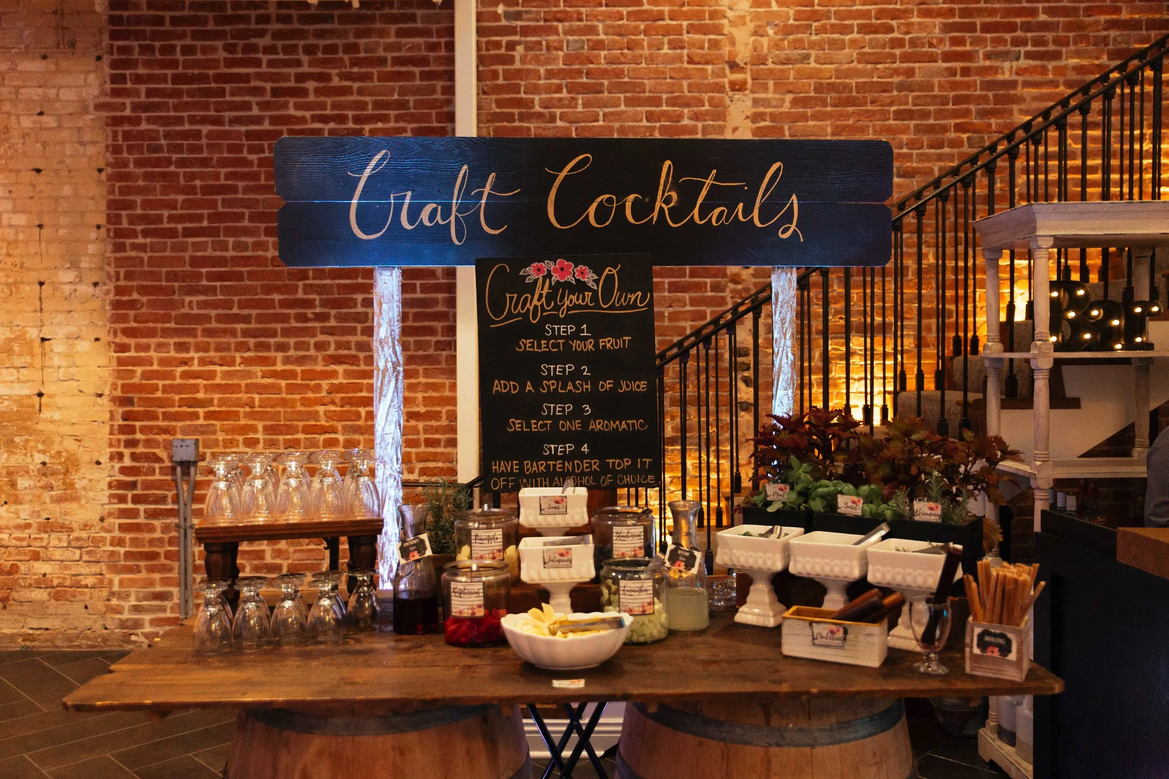 Craft cocktail station beside a brick wall and staircase