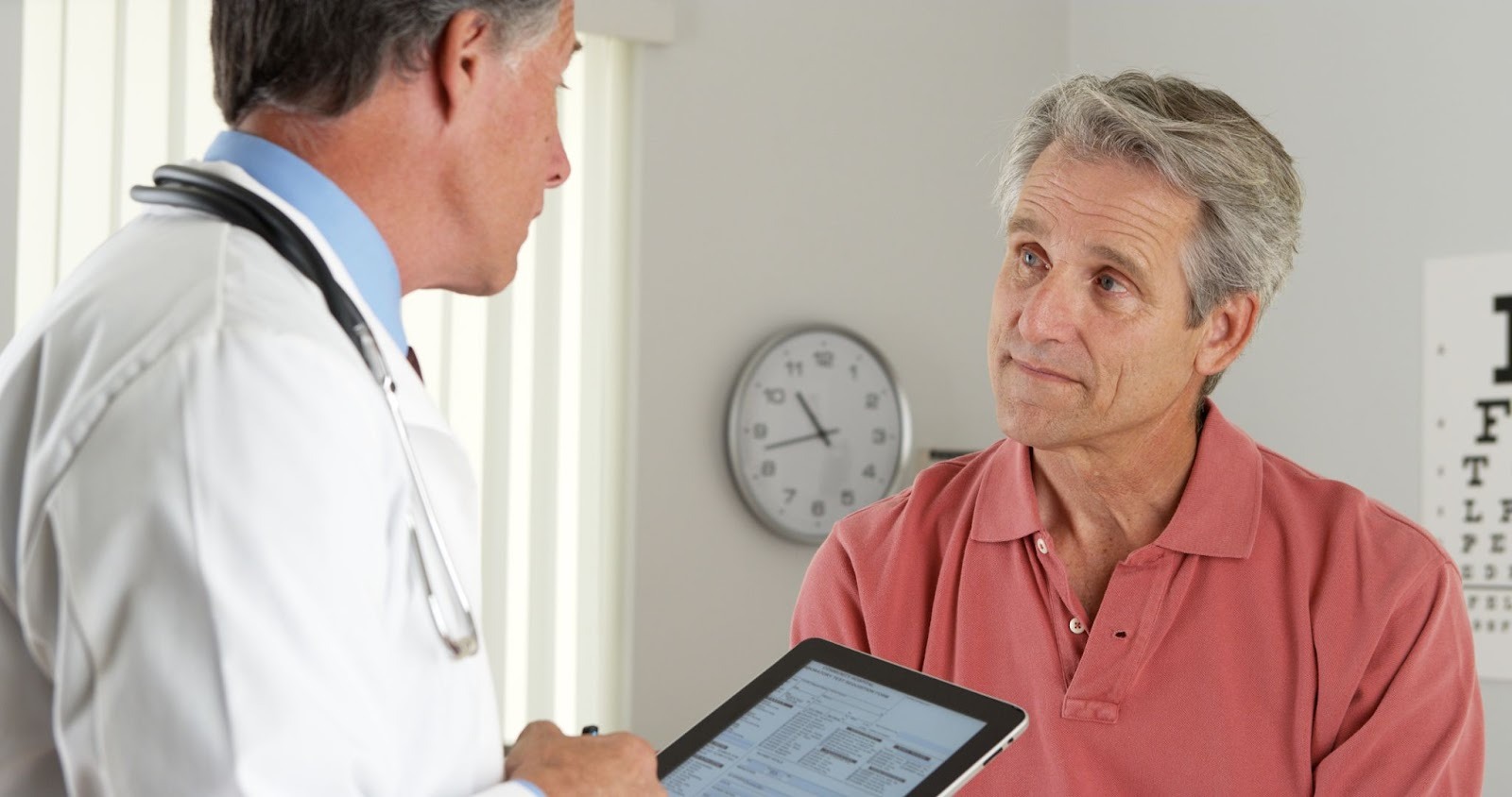 Male urologist discussing treatment options for enlarged prostate with an older male patient in a clinic setting.