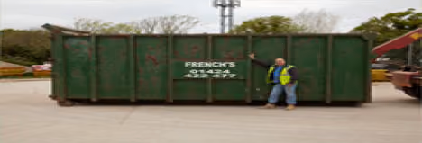 A person in a yellow vest stands next to a large green container labeled "FRENCH'S."