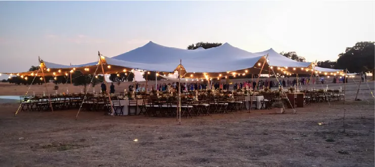 Stretch tent with dinner tables and lights at dusk