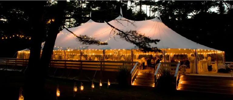 Sailcloth tent lit up at night at a wedding among the trees