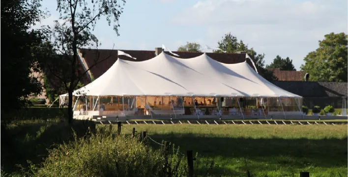 White sailcloth tent set up in a garden for a wedding