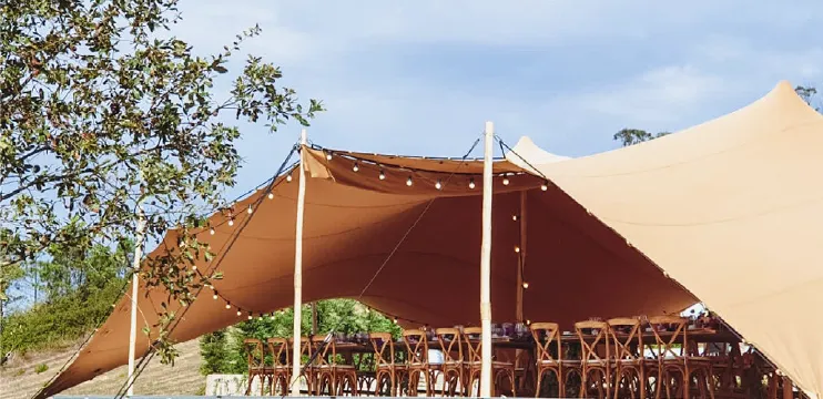 Terracotta stretch tent with wooden tables and hanging lights