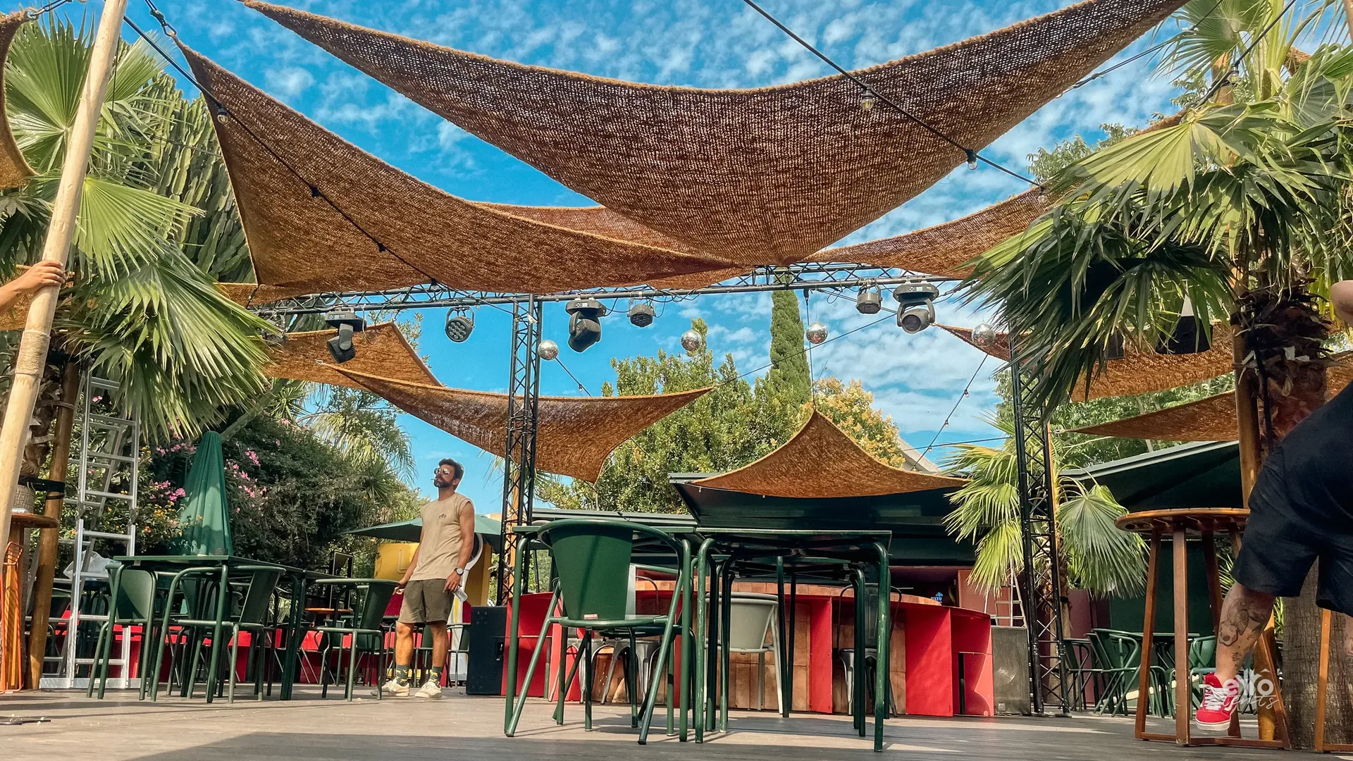 Woven shade sails over a terrace with palm trees