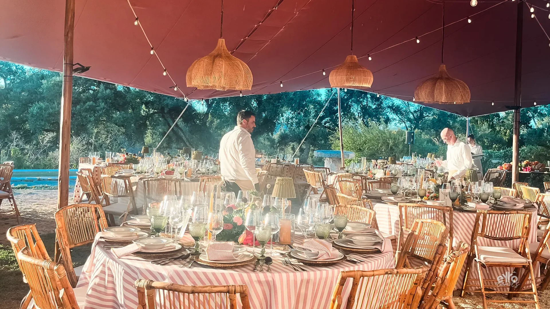 Round tables under a stretch tent with wicker lamps