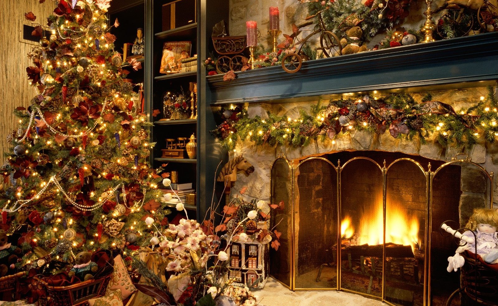 christmas tree decorated in gold and burgundy in front of a highly decorated fireplace
