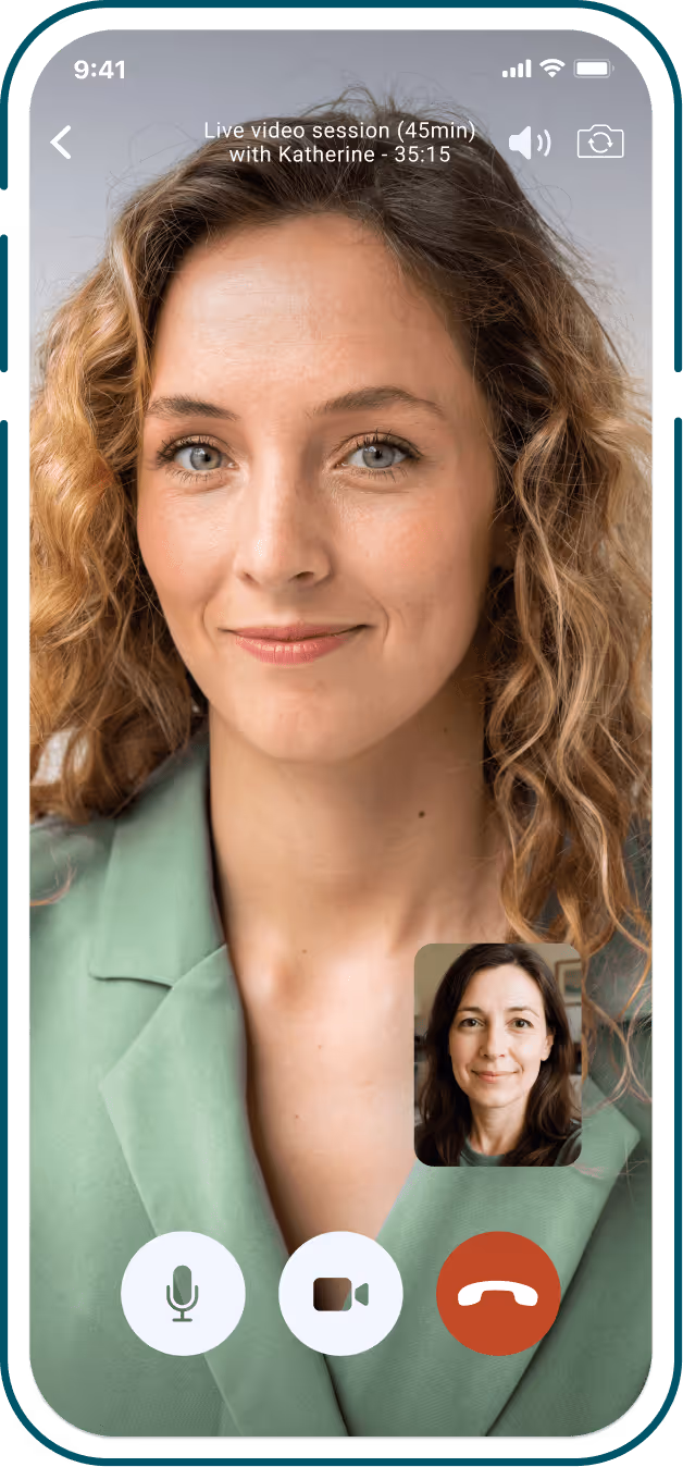 Smartphone screen showing a live video call session with a smiling woman with curly hair wearing a green blazer, and a smaller inset of another smiling woman with dark hair.