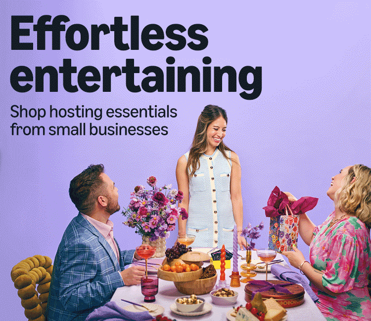 GIF of three people at a dinner party, one person is receiving a gift
