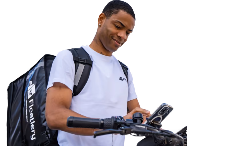 Delivery person wearing a white Fleetlery shirt and backpack checks phone while holding handlebar.