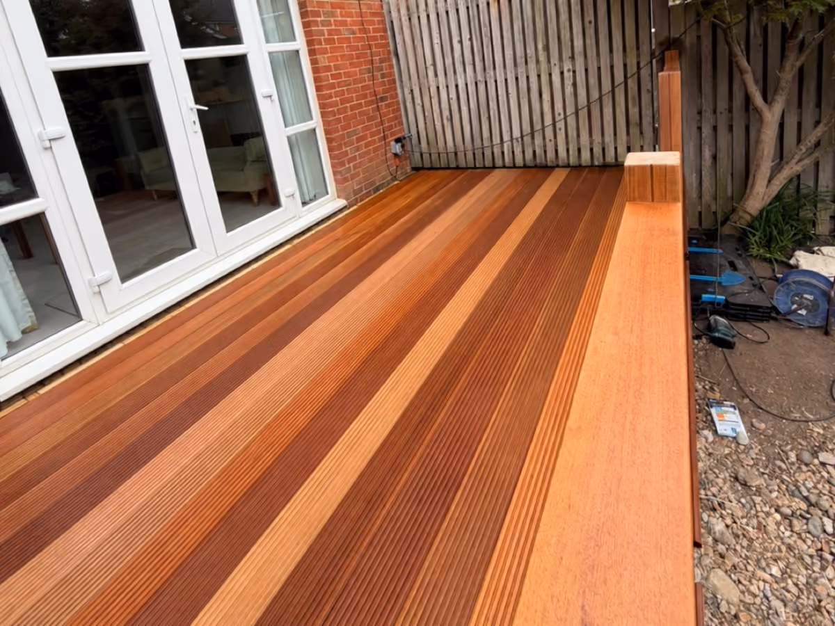 View along newly installed timber decking and a wooden handrail beside patio doors during construction