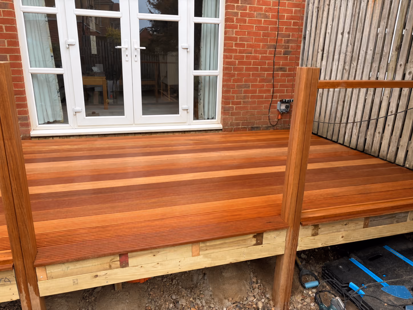 Newly installed timber decking with railing posts and exposed supporting framework during construction