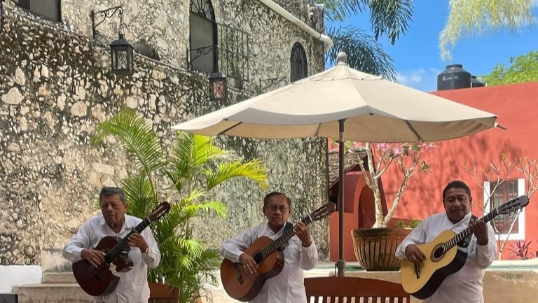 a group of mariachis playing their guitars on a patio in Mexico