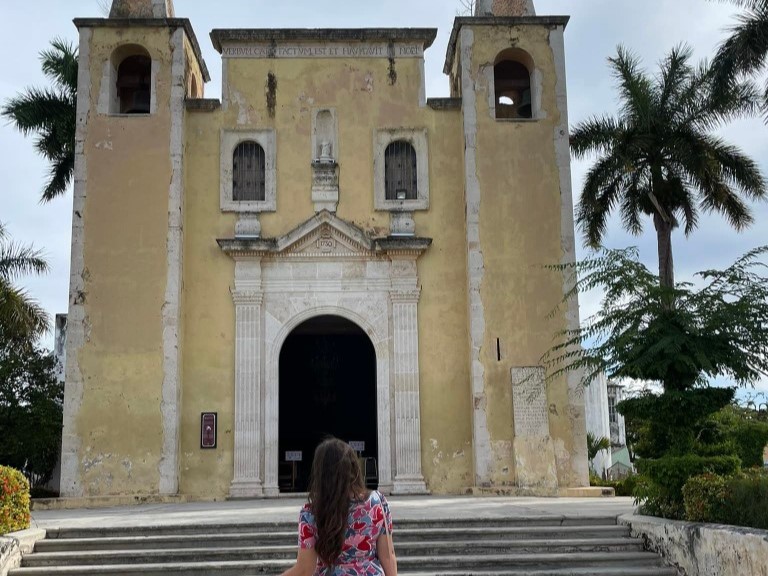 a woman standing with her back to the camera facing an old church in Mexico
