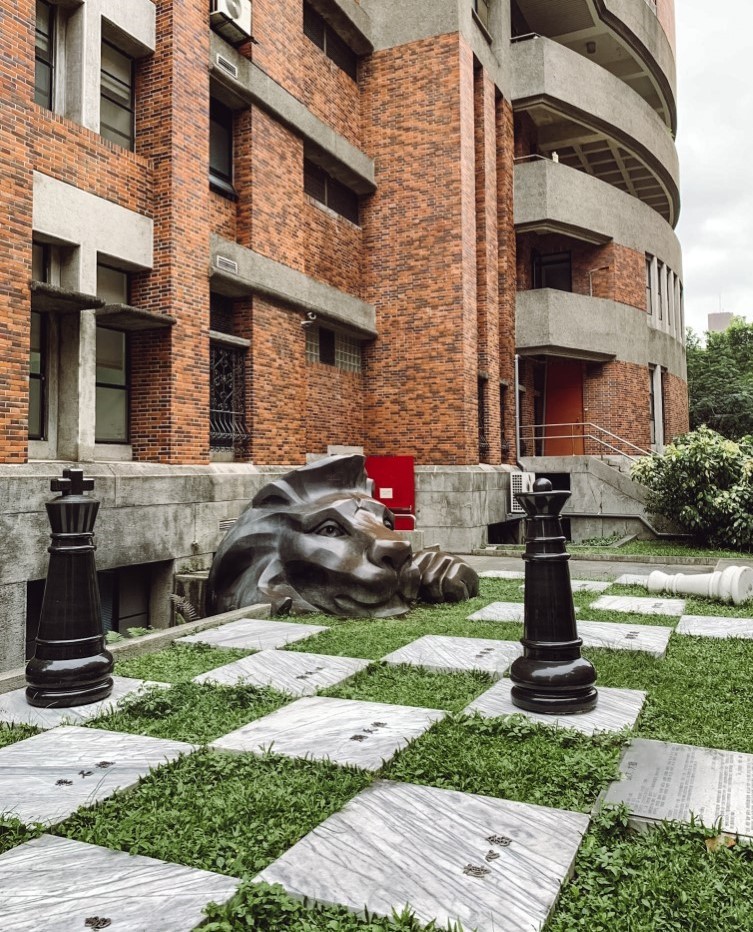 View of Shida campus in Taiwan with a brick building and a lion statue on a giant chess board