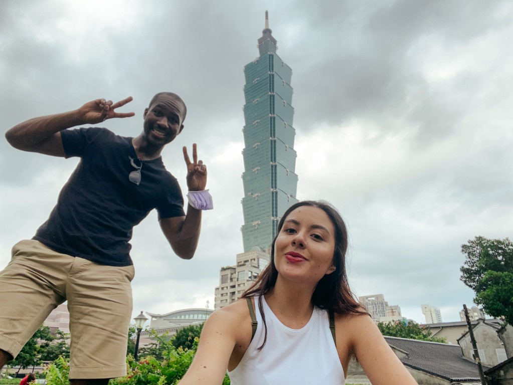 Colombian woman and American partner, living abroad in Taiwan, posing in front of the tall building, Taiwan 101