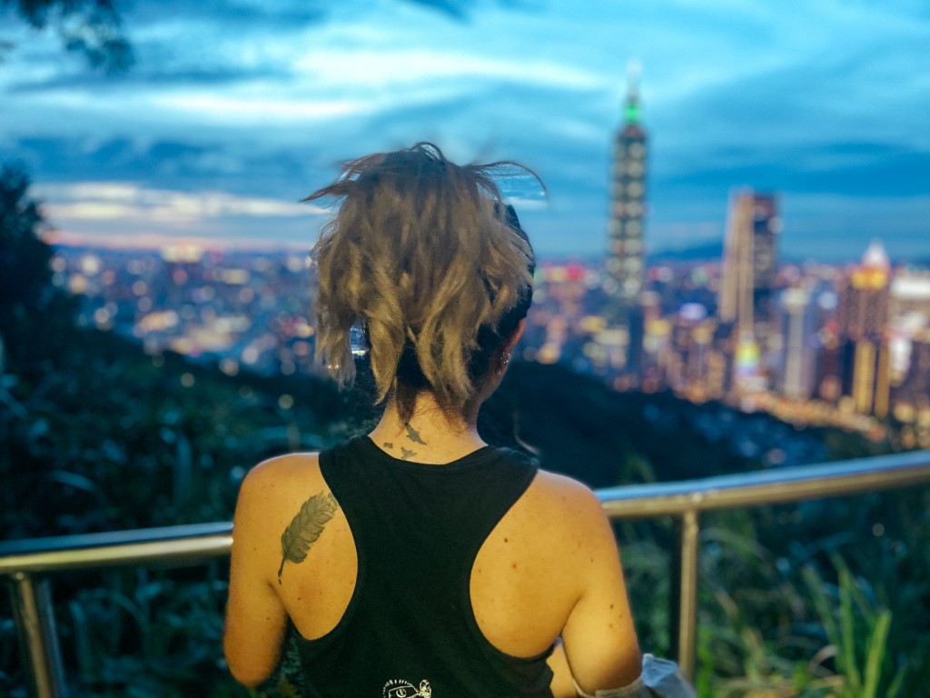 A view of Taipei's skyline at sunrise with the backside of a woman in the foreground