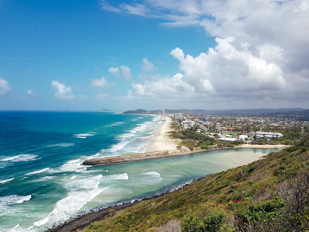 View of the lesser developed coastline on The Gold Coast with trees, beach, blue water and some small buildings
