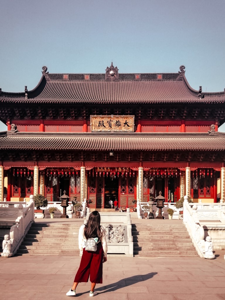 a woman with her back to the camera looking at an ancient temple in china