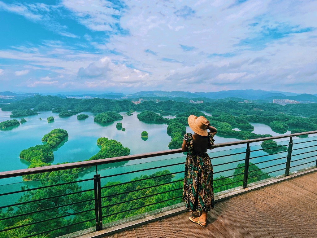 a woman overlooking Thousand Islands in China, a water reservoir with thousands of small, green islands