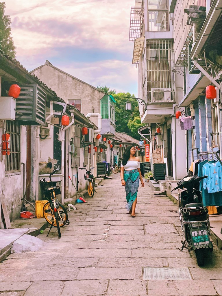 a woman walking through the alleys of a small town in china