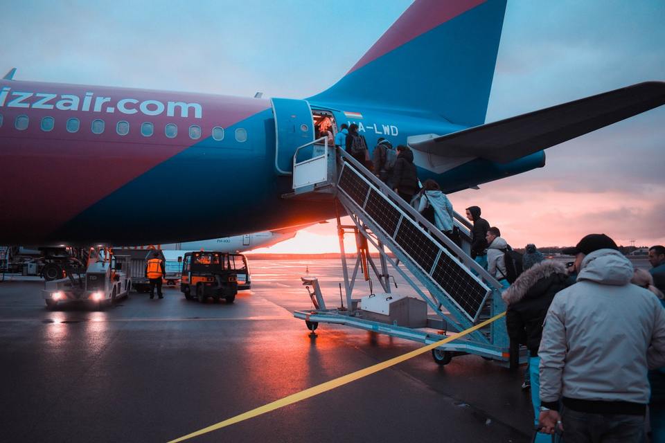 Line of people boarding a flight outside at sunrise