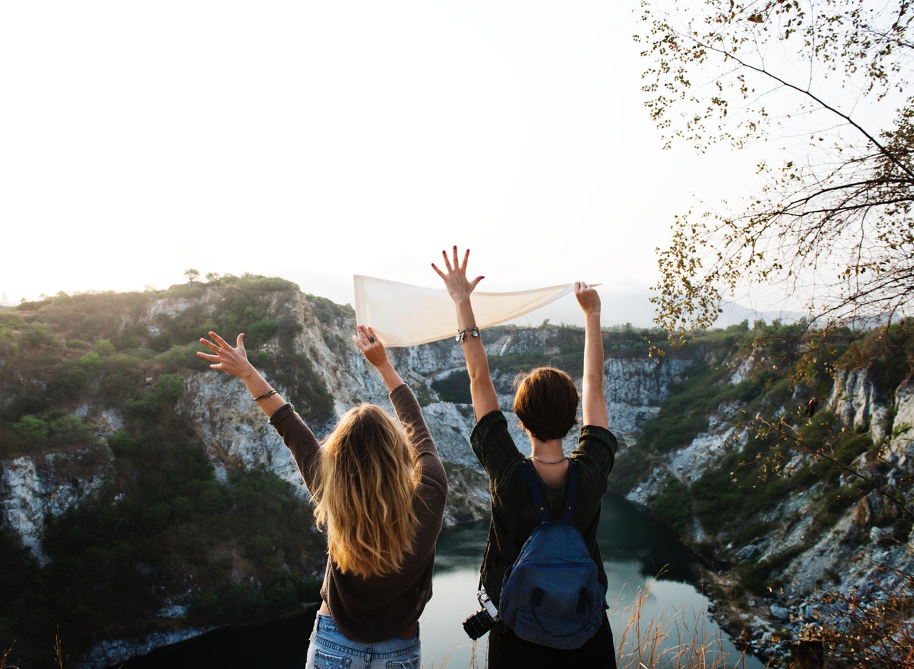 2 women holding a white flag over lookout point on hike