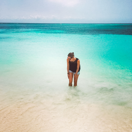 Female international travel nurse splashing in the water in Aruba
