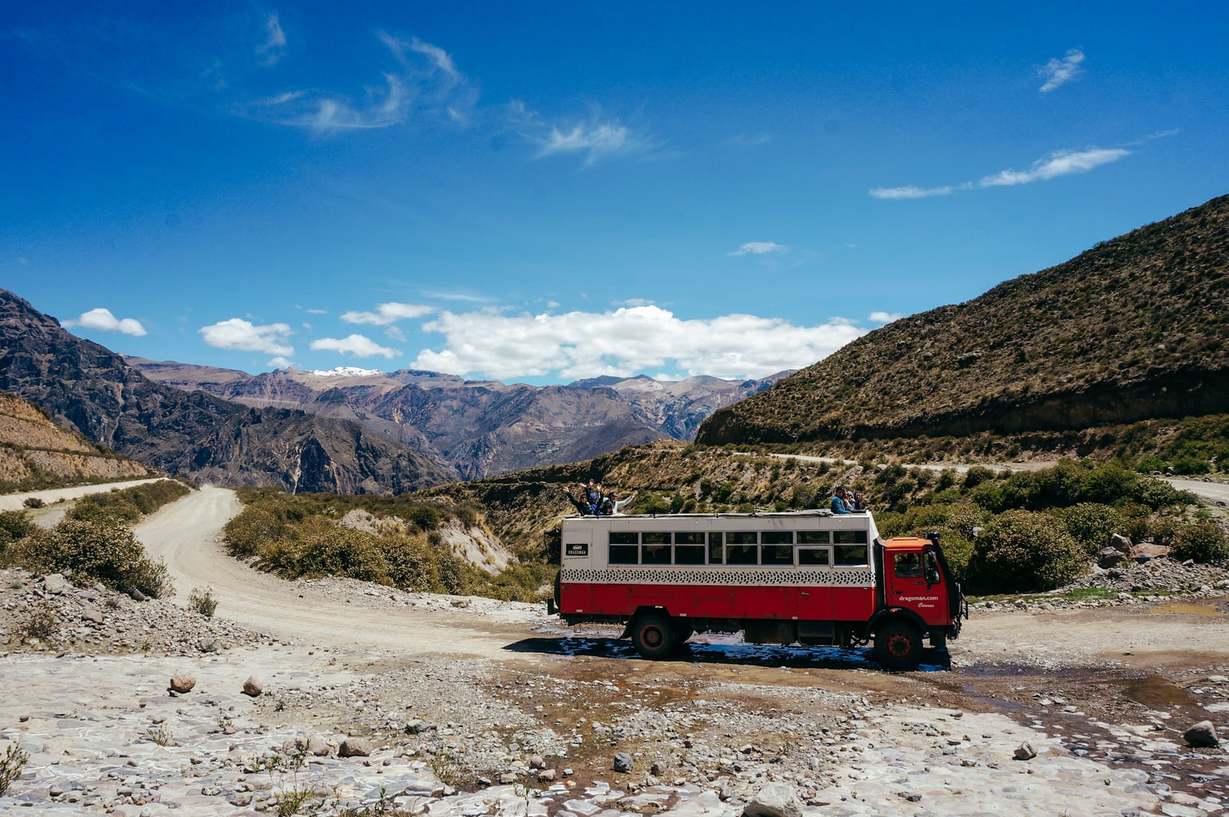 Overland red and white Dragoman Tour bus parked at Colca Canyon, Peru.
