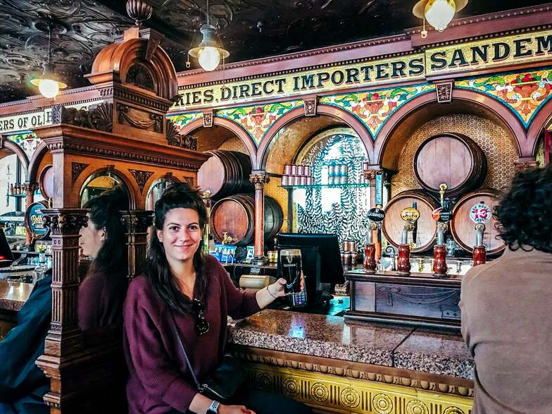 A woman sitting at the bar enjoying a pint of Guiness at an Irish pub