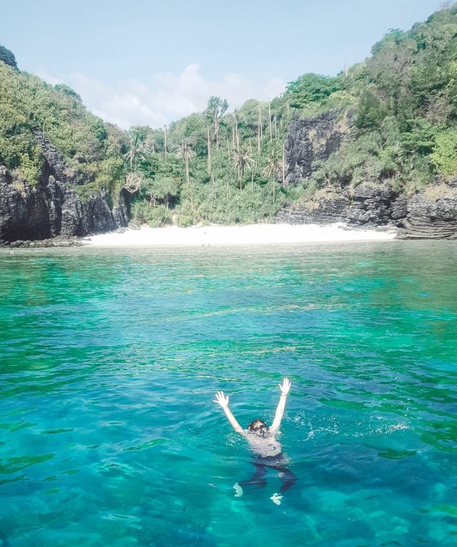 A female tourist in Thailand snorkeling at a hidden beach on the Phi Phi Islands