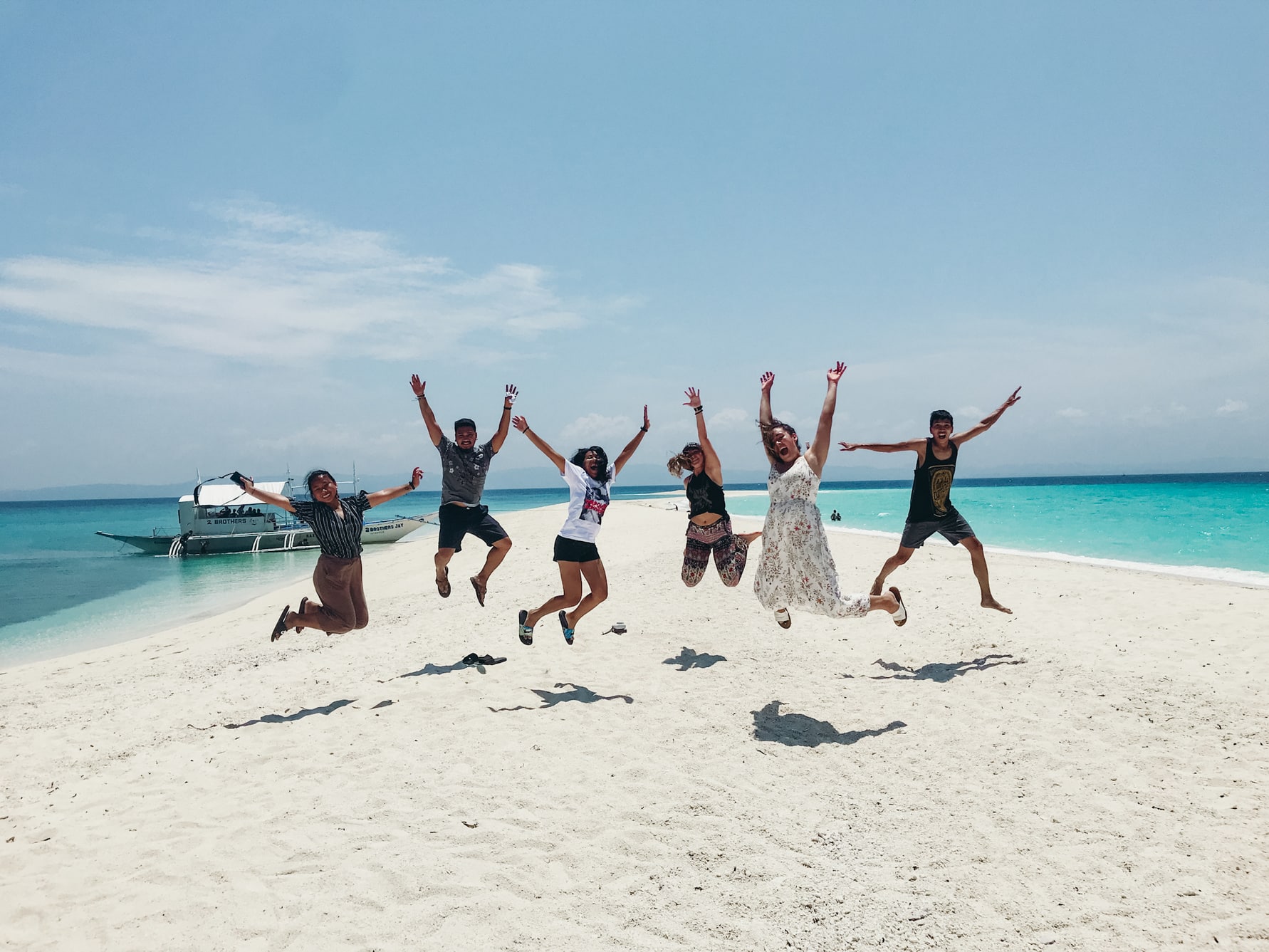 Friends jumping on a small strip of beach in the Philippines