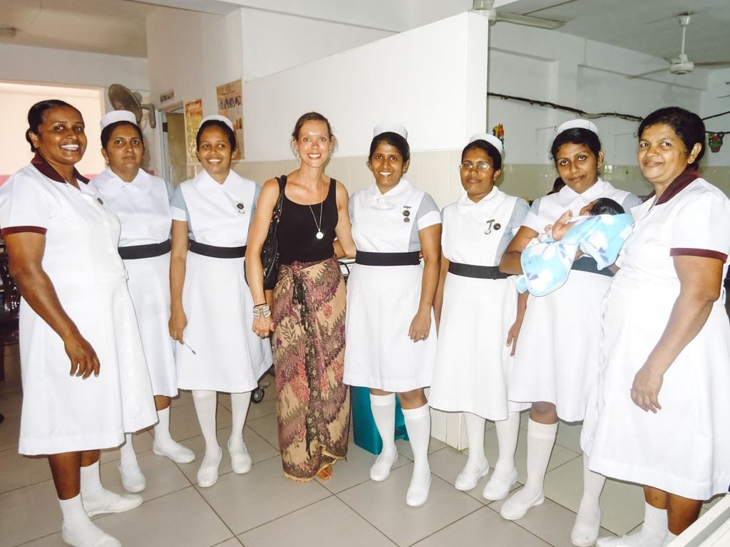 An international travel nurse smiling with a group of local nurses while on a tour of the hospital