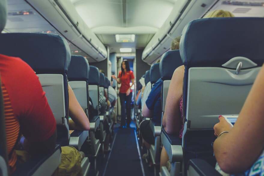 View of a typical airplane aisle with passengers and flight attendant