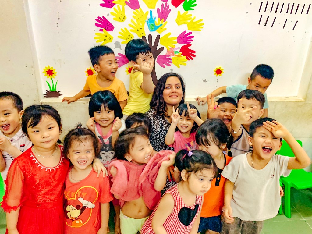 English teacher posing with a group of young, smiling students in Vietnam