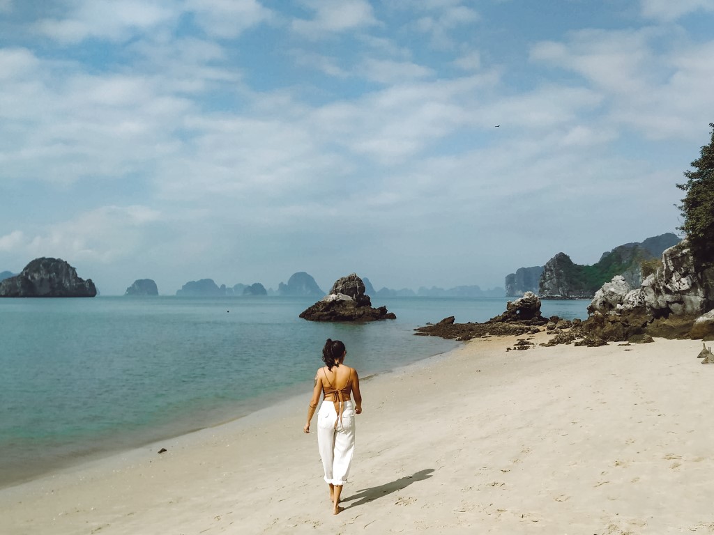 A digital nomad taking advantage of being location independent strolling the beach in Ha Long Bay, Vietnam