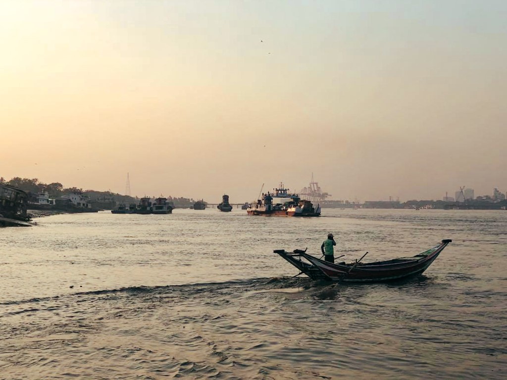the yangon river at sunset with small fisher boats and bigger barges