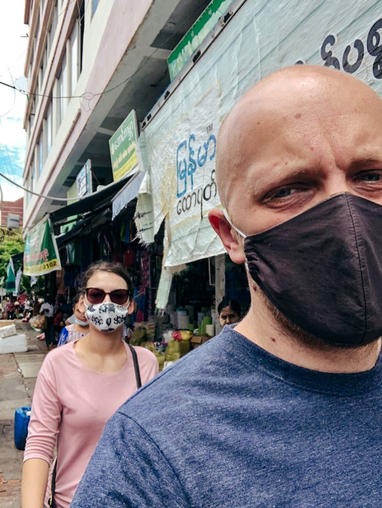 a foreign couple living abroad in myanmar during coronavirus, wearing masks, walking through the local market