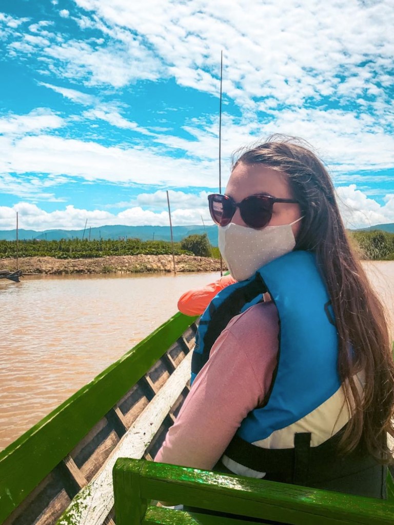 A female expat living abroad in Myanmar, wearing her face mask on a boat trip.