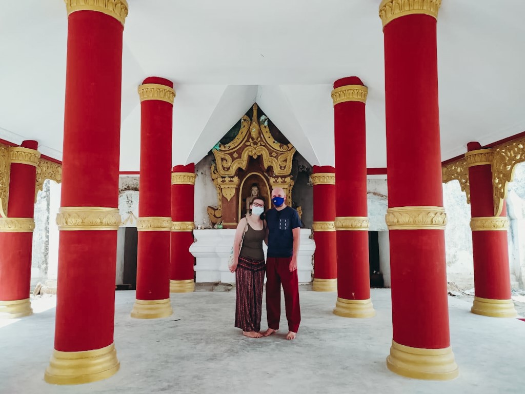 A foreign couple living in Myamar, exploring local temples without any tourists, wearing a face mask and no shoes