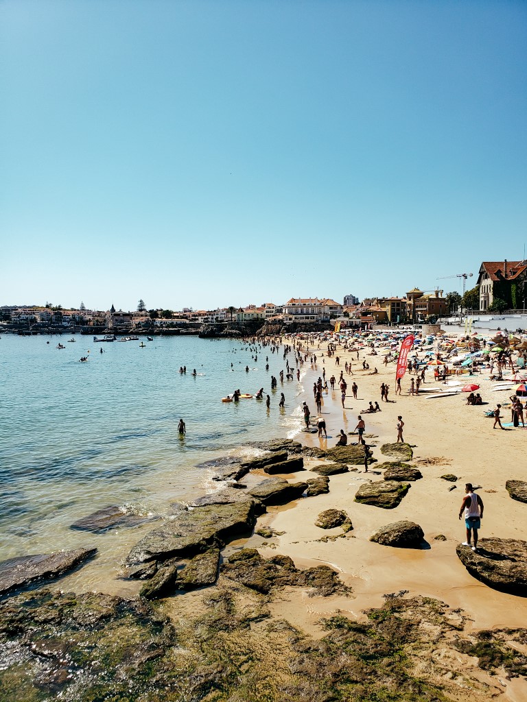 a crowded beach during the afternoon with many people in the sand