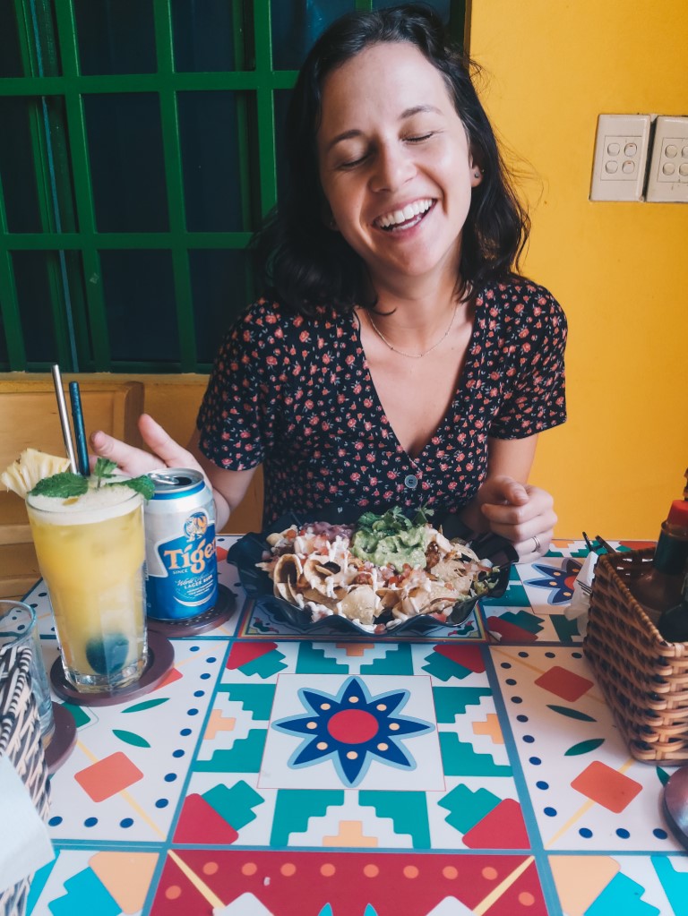 A woman closing her eyes and smiling at the camera ready to eat at a Mexican restaurant